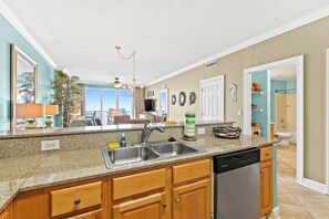 A kitchen with granite countertops, wooden cabinets, a dishwasher, and a double sink. - 16-floor beachfront condo with amazing views, indoor/outdoor pools, & hot tub (Panama City Beach)
