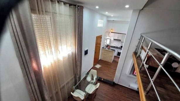 Um apartamento moderno com área de jantar, cozinha e escada.