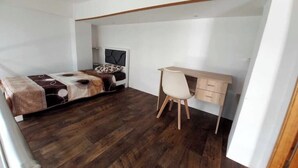 Quarto com cama, escrivaninha e cadeira.