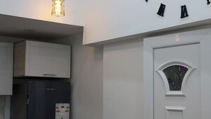 Cozinha com armários brancos, uma geladeira preta e um relógio decorativo na parede.