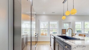 Cozinha moderna com uma ilha grande, eletrodomésticos de aço inoxidável e vista para o exterior.