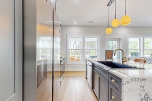 A modern kitchen with a large island, stainless steel appliances, and a view of the outdoors.