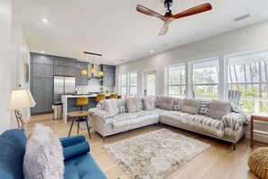 Un salon moderne avec un canapé d’angle, un fauteuil bleu et un tapis à poils longs blanc.