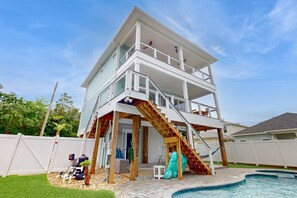 Une maison à deux étages avec un balcon, une piscine et une terrasse en bois.