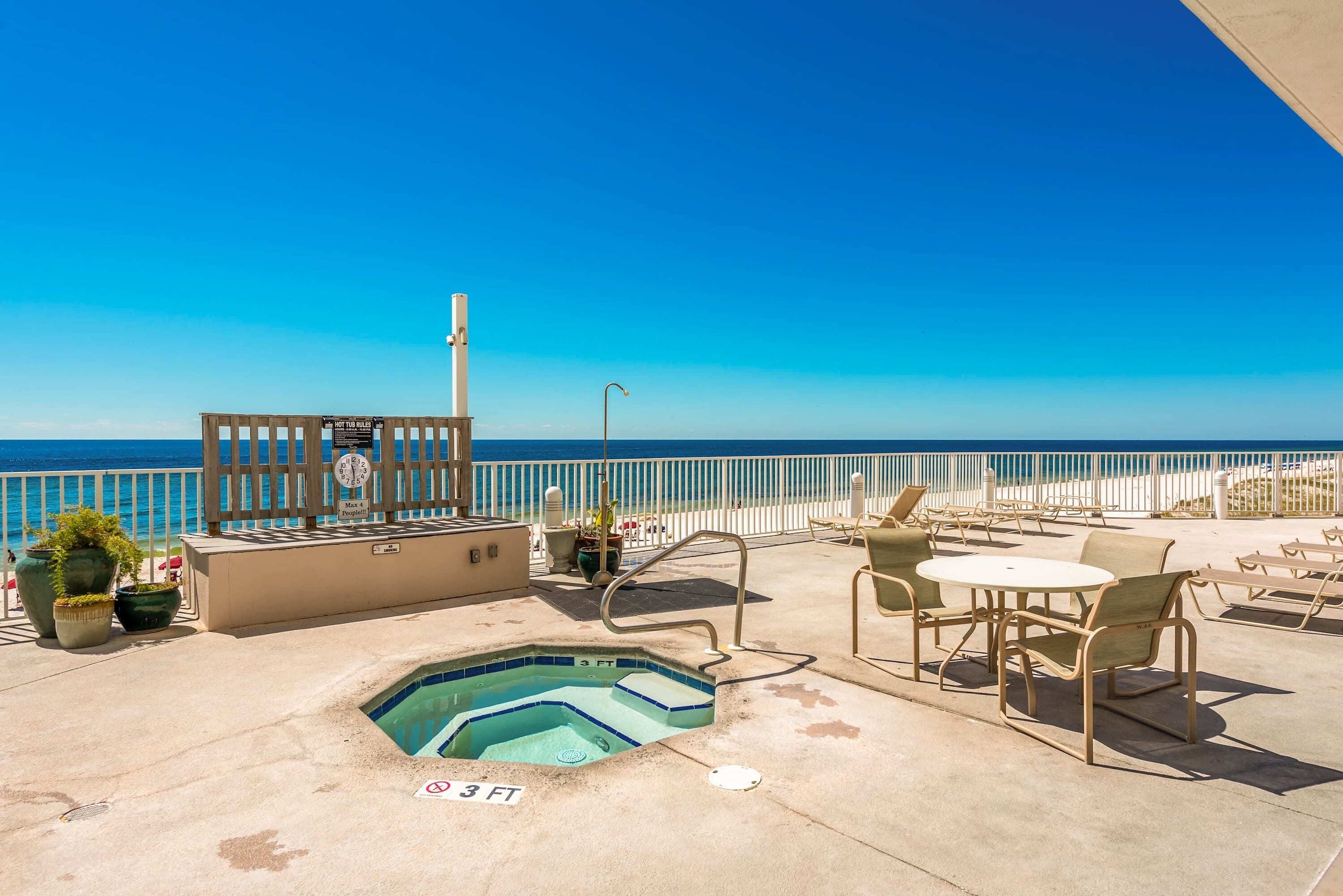 A rooftop pool area with a view of the ocean, outdoor seating, and a sign indicating a 3-foot depth.