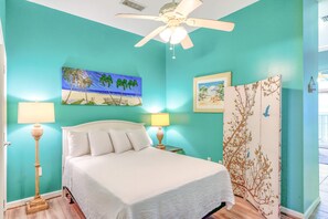 A bedroom with a bed, two bedside lamps, a ceiling fan, and artwork on the walls. - Inviting Gulf-front condo In Perdido Key with waterfront pool/hot tub and oceanfront balcony (Perdido Key)