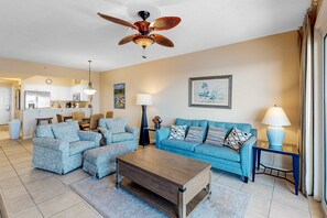 A living room with a blue sofa, matching ottoman, and a wooden coffee table. - Inviting Gulf-front condo In Perdido Key with waterfront pool/hot tub and oceanfront balcony (Perdido Key)