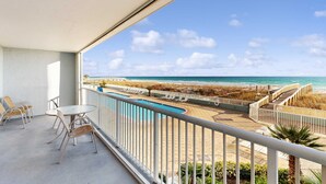 Un balcon avec vue sur une plage et une piscine.