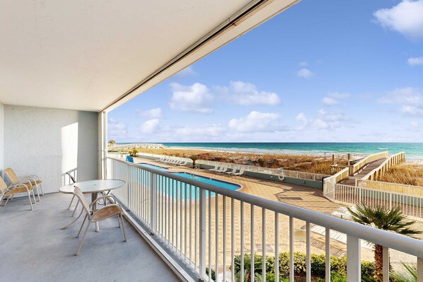 Un balcón con vista a la playa y a la piscina.