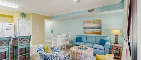 A living room with a blue sofa, a round coffee table, and a ceiling fan.