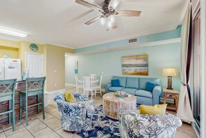 Ein Wohnzimmer mit einem blauen Sofa, einem runden Couchtisch und einem Deckenventilator.