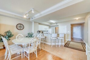 A modern kitchen with white cabinets, a central island, and bar stools. - Welcoming, beachfront condo with Gulf views, pools & fitness center (Panama City Beach)