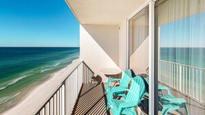 A balcony with a view of the ocean, a round table, and turquoise chairs. - Exclusive Gulf-front condo | panoramic views | Pools & Hot tub (Panama City Beach)