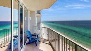 Un balcone con vista sull'oceano e un molo. Si notano due sedie blu e un tavolo.