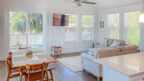 Un espacio habitable luminoso y amplio con una mesa de comedor, sillas, un sofá y un ventilador de techo.