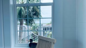Una habitación con un ventanal grande que da a una cerca blanca y palmeras.