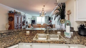 Una cocina con encimeras de granito, un lavabo doble y una zona de comedor con mobiliario de mimbre.