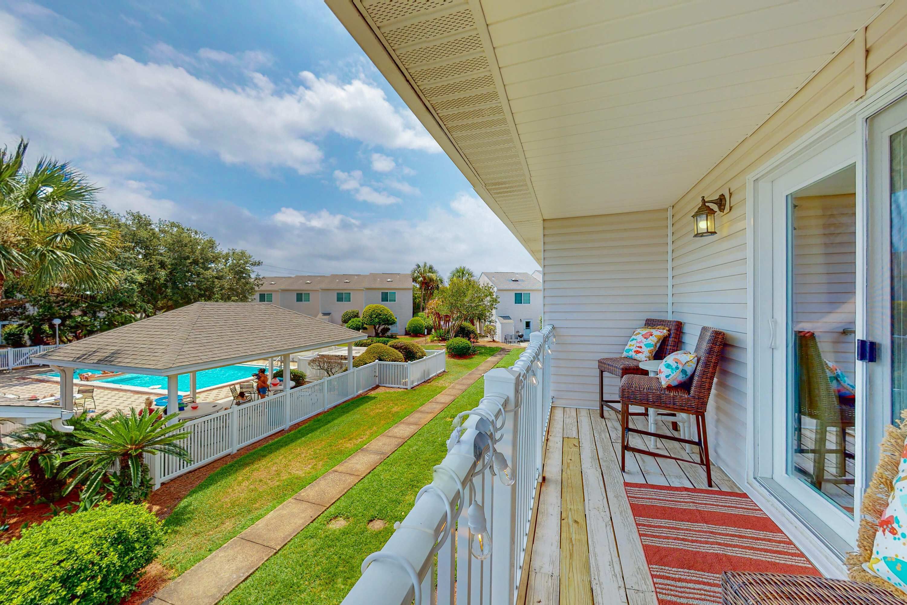A covered outdoor area with a pool, a lawn, and a seating area with chairs and a table.
