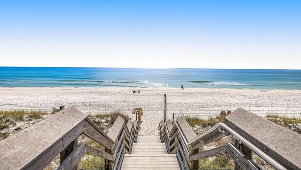 Un escalier en bois mène à une plage d’où l’on a une vue dégagée sur l’océan.