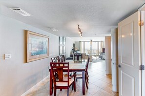 A dining area with a table and chairs, a ceiling fan, and a framed picture on the wall. - 9th-floor, Gulf-front condo with spectacular views, pool, beach access & private balcony (Perdido Key)