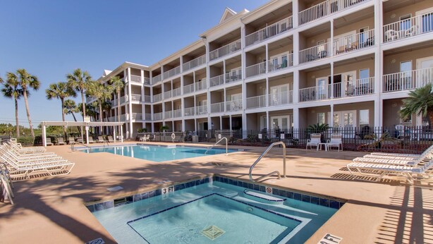 A hotel with a pool area, multiple balconies, and palm trees. - Updated condo with balcony, central AC, pools, hot tub, grills, & beach access (Perdido Key)