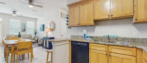 Una cocina moderna con armarios de madera, encimera de granito y lavavajillas.