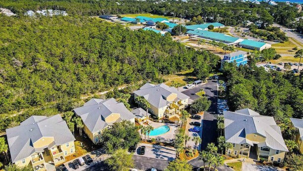 Zona residencial com várias casas, uma piscina e um edifício grande com telhado azul.