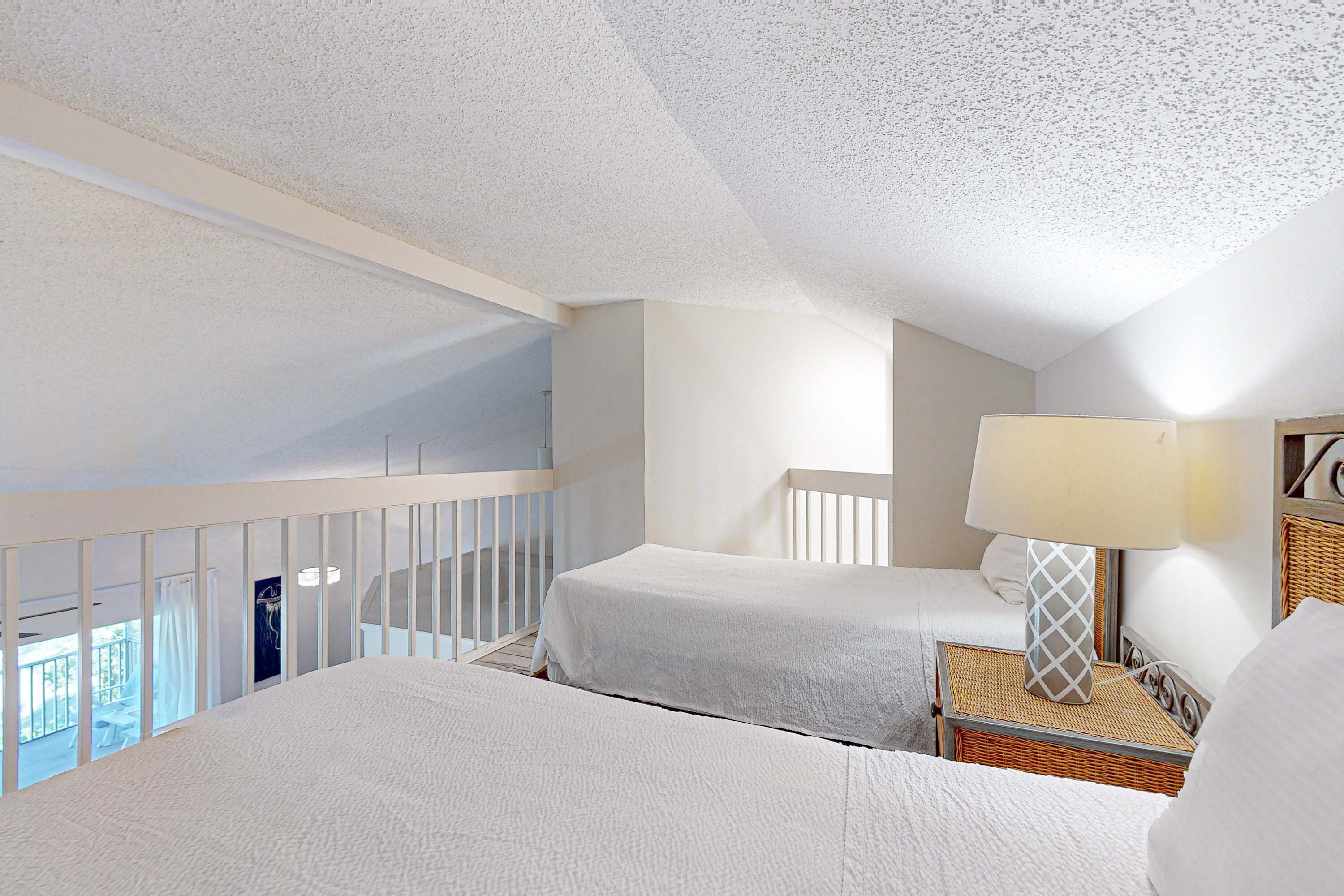A hotel room with two beds, a balcony, and a lamp.