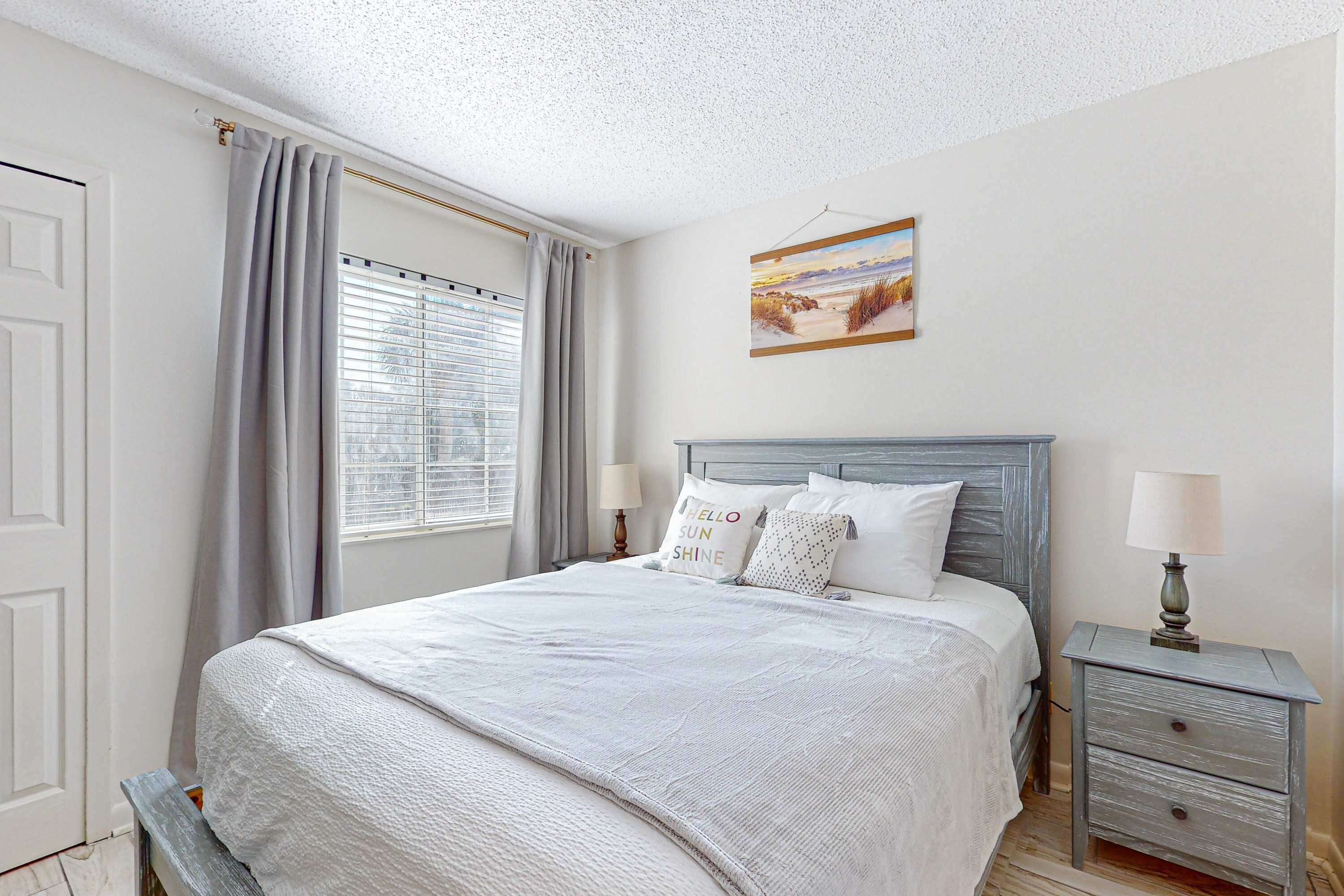 A neatly arranged bedroom with a bed, bedside tables, and a window with curtains.