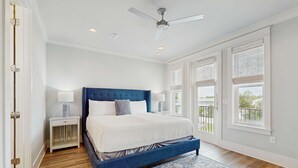 A bedroom with a bed, nightstand, and a view of the outdoors. - Beautiful White Coral Chateau (Miramar Beach)