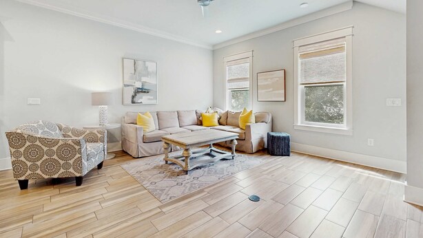 A spacious living room with a beige sofa, patterned armchair, and a wooden coffee table. - Beautiful White Coral Chateau (Miramar Beach)