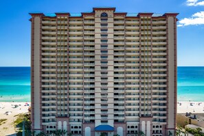 A tall hotel with multiple balconies, a beach view, and a pool area. - Stunning Gulf-front condo with balcony, pool, hot tub, gym & beach views (Panama City Beach)