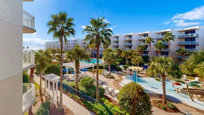 Ett semesterhotell med poolområde, palmer och utsikt över havet.