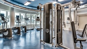 Ett gym med olika typer av träningsutrustning, stora fönster och ett blått tak.