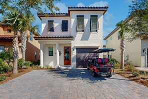 A two-story house with a garage, a driveway, and a golf cart parked in front. - Villa Lago - Seaside Sanctuary (Miramar Beach)