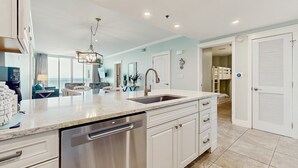 Una cocina moderna con lavavajillas, un lavamanos y una zona de comedor con candelabro.