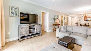 A living room with a television, sofa, and ottoman. - Ground-Floor Condo At Waterscape 490 Feet Of Private Beach (Fort Walton Beach)