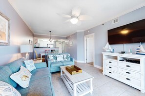 A living room with a sofa, coffee table, TV stand, and ceiling fan. - Fourth Floor, Oceanfront Condo At Waterscape with Shared Pool & Hot Tub (Fort Walton Beach)