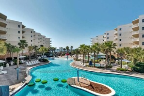 A swimming pool with multiple lanes, surrounded by lounge chairs and palm trees. - Beachy Gulf-front condo at Waterscape Washer&dryer in-unit 490 feet of beach (Fort Walton Beach)