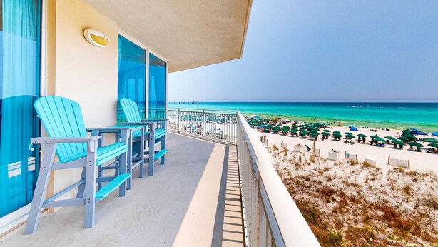 A balcony with blue Adirondack chairs, a view of the beach, and a clear sky. - Beachfront Condo with Private Beach & Access, Balcony, Ocean View, & WiFi (Fort Walton Beach)
