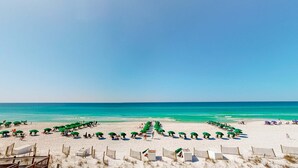 A beach with rows of green umbrellas and beach chairs, a wooden fence, and a clear blue sky. - Beachfront Condo with Private Beach & Access, Balcony, Ocean View, & WiFi (Fort Walton Beach)
