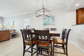 Un coin repas avec une table et des chaises en bois, un lustre et un tableau au mur.