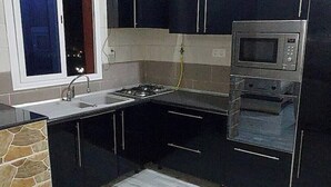 A modern kitchen with black cabinets, a gas stove, a microwave, and a sink. - Whole house: apartment - Béjaïa, Algeria (Béjaïa)