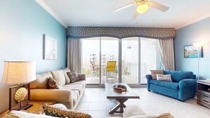 Ein Wohnzimmer mit einer Couch, einem blauen Sofa, einem Couchtisch und einem Deckenventilator.