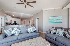 A modern living room with a grey sofa set, a wooden coffee table, and a ceiling fan. - Incredible Gulf-Front Condo On Okaloosa Island 490 Feet Of Private Beach (Fort Walton Beach)