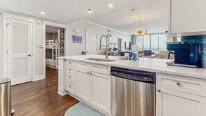 Una cucina moderna con mobili bianchi, elettrodomestici in acciaio inossidabile e lavastoviglie integrata.