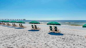 A beach with rows of green umbrellas and wooden lounge chairs. - 5th Floor Lovely Condo At Waterscape Waterfall, Lazy River (Fort Walton Beach)