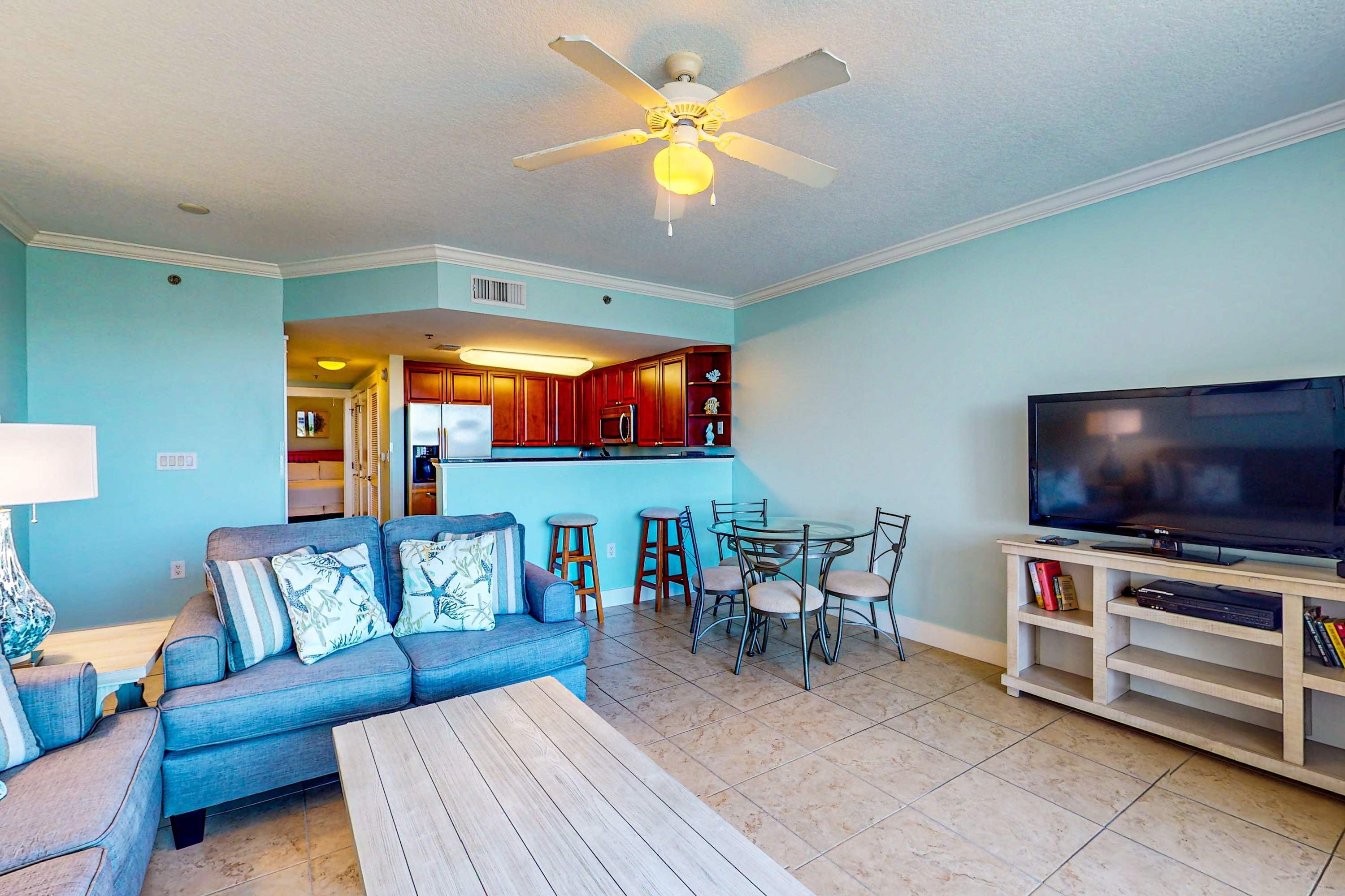 A living room with a sofa, coffee table, TV, and a dining area with chairs and a table.
