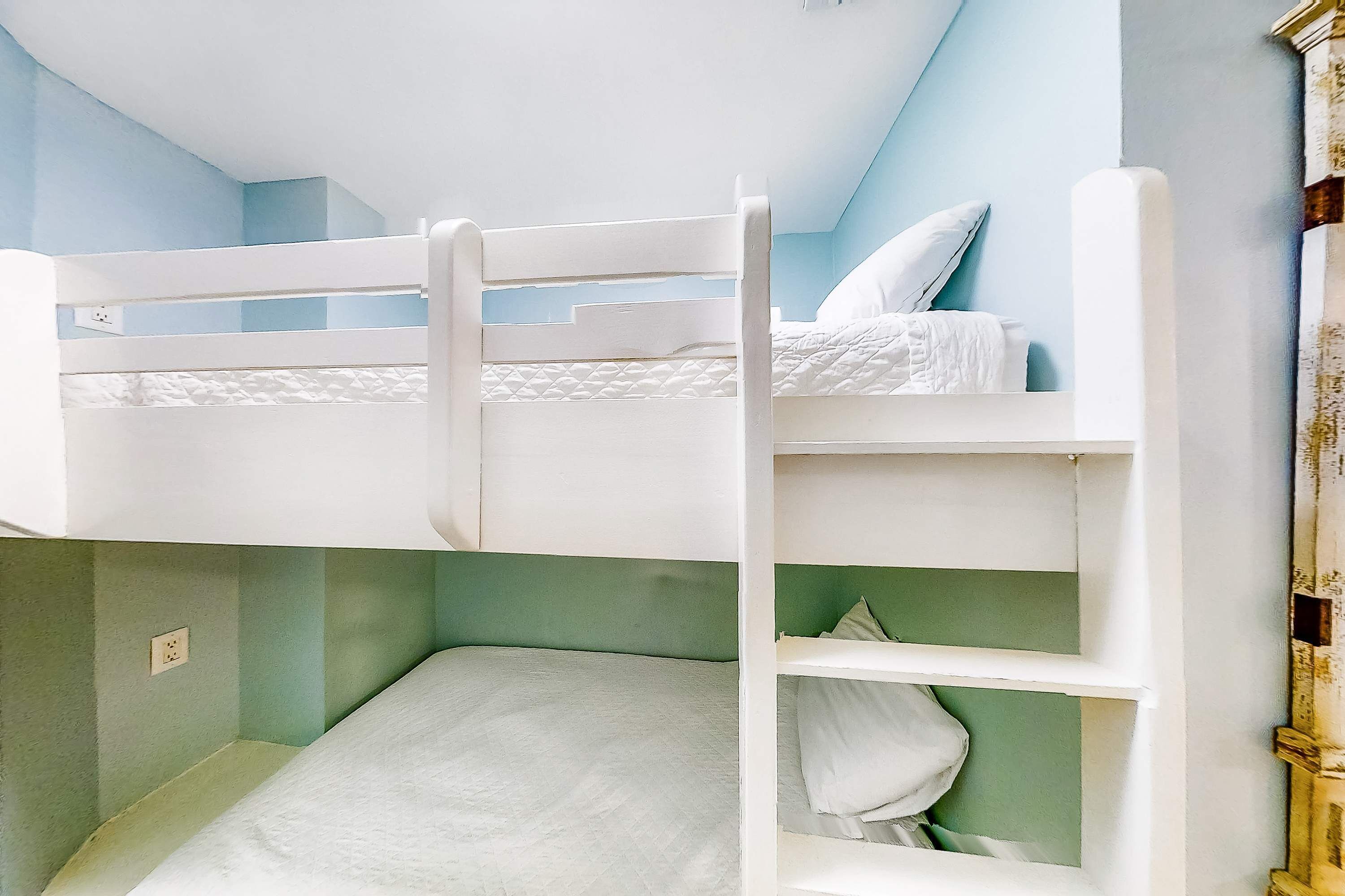 Quarto com beliche, parede verde e teto branco.