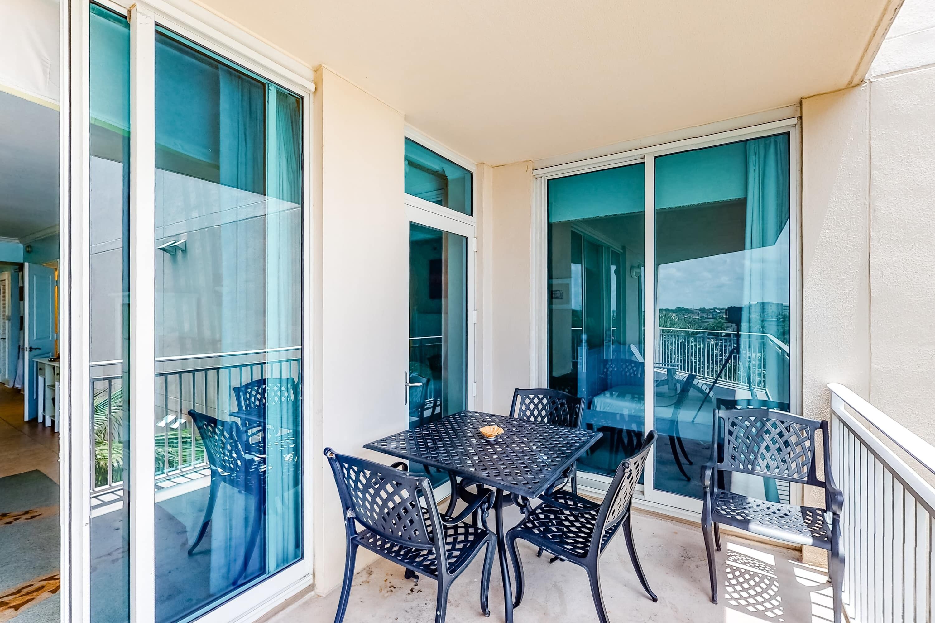 Ein Balkon mit Tisch und Stühlen, großen Fenstern und Blick auf die Stadt.